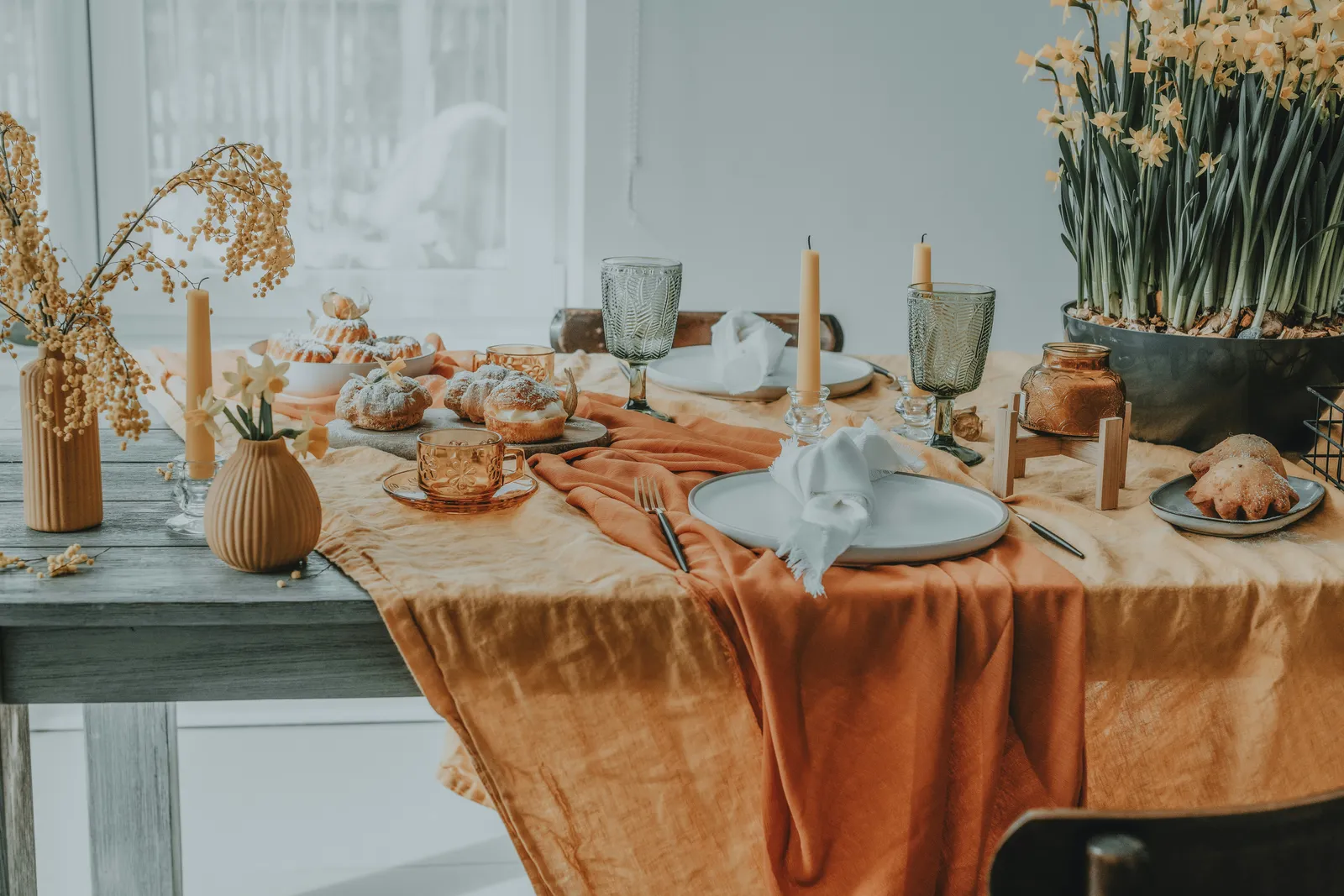 Table dressée avec assiettes, verres et fleurs.